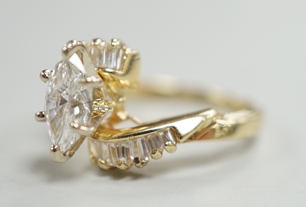 A yellow metal and singe stone marquise cut diamond set crossover dress ring, with baguette cut diamond set shoulders, size J/K, gross weight 3.2 grams.